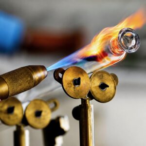 Technician forming quartz tubing into a UV curing lamp body using a precision glassworking torch at TCS Technologies.