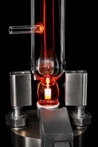Rotary glassblowing torch sealing a quartz side tube onto a UV curing lamp during precision quartz manufacturing at TCS Technologies in the USA.